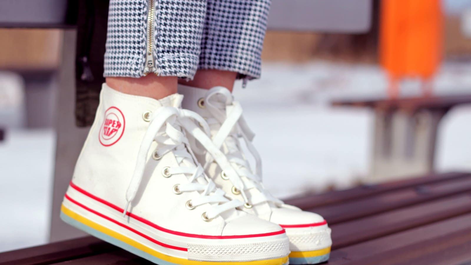 Sneaker montante blanche portée, vue de profil sur un banc