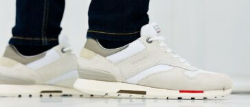 Sneakers en daim beige portées avec un jean, vue de profil au sol