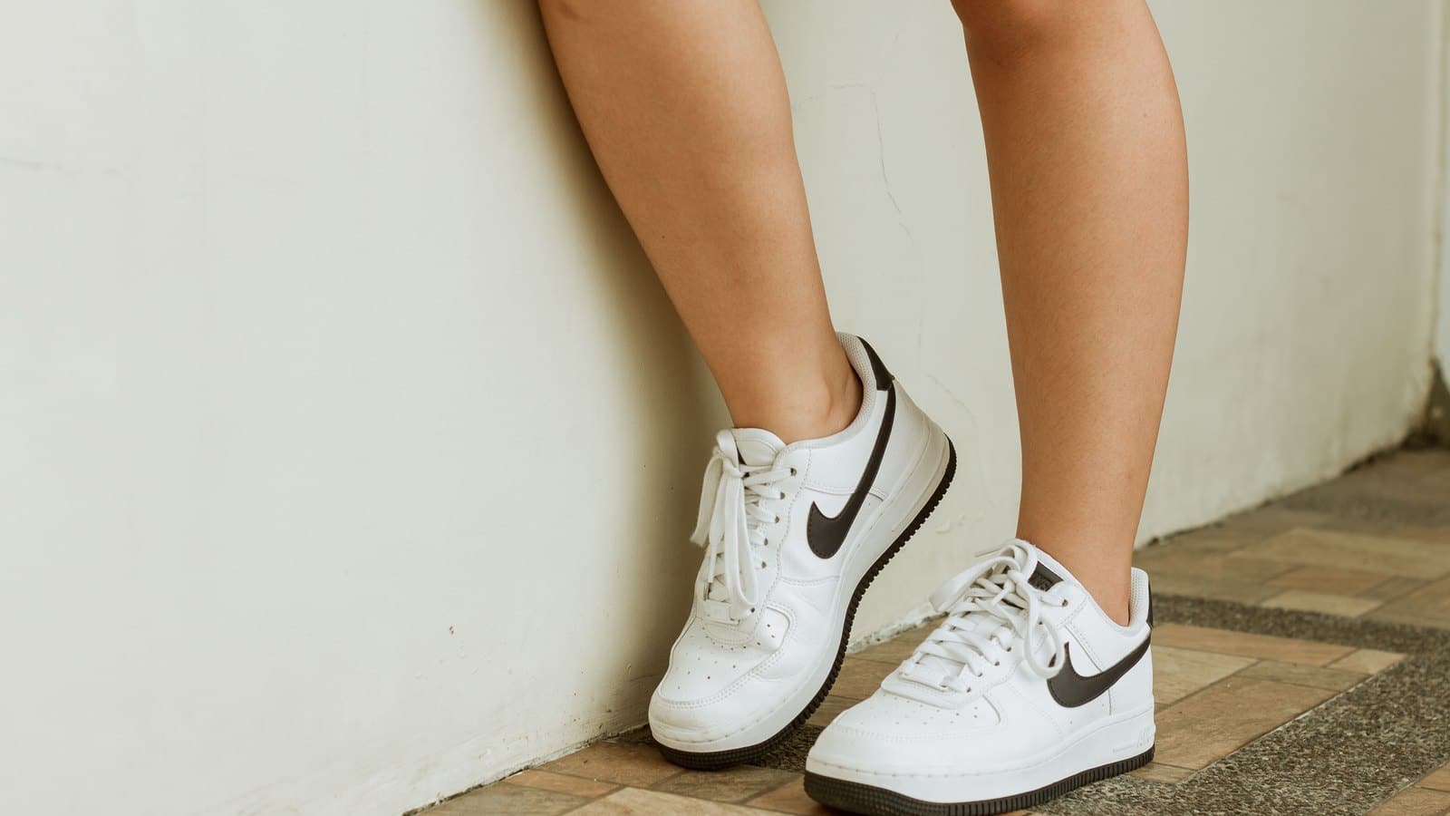 Sneakers blanches Nike portées, vues de trois quarts contre un mur