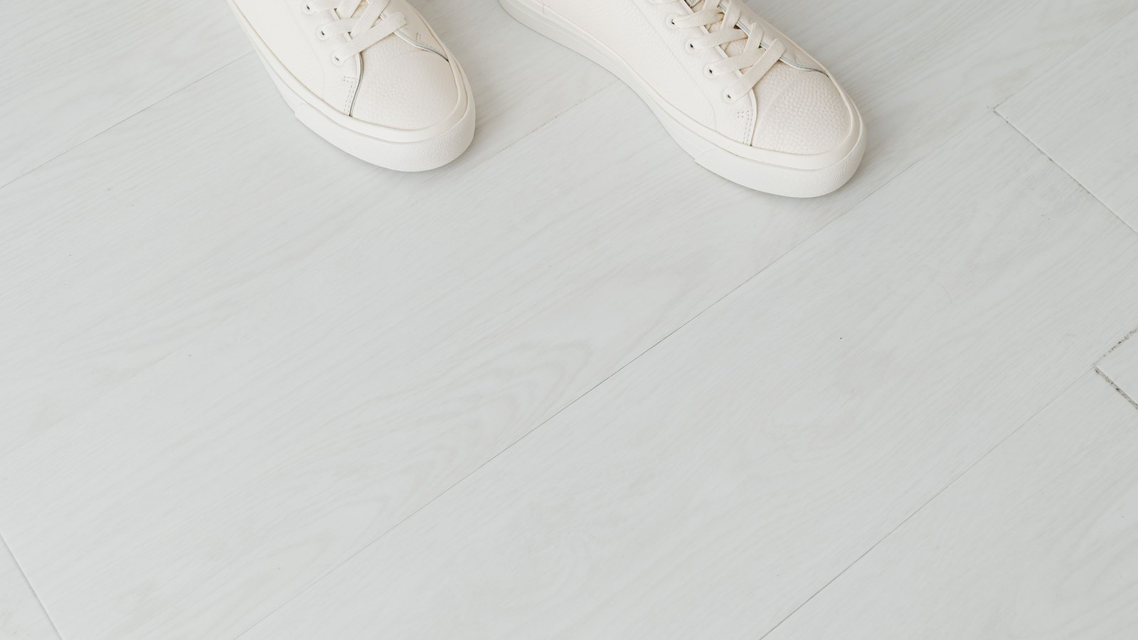 Paire de sneakers blanches en cuir posées sur un sol clair