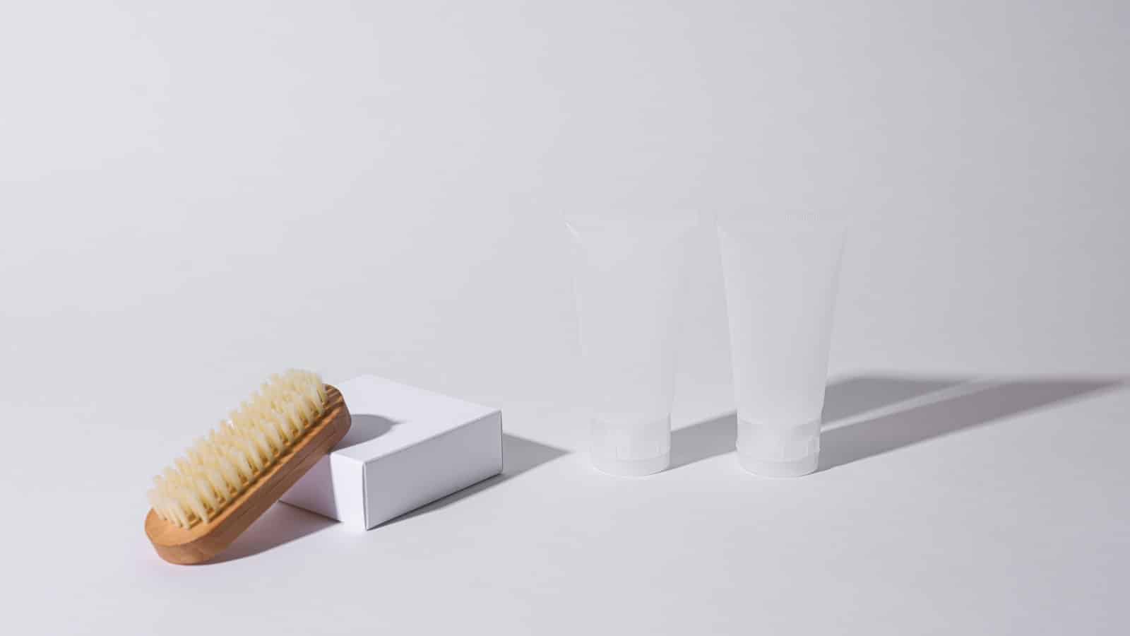 Brosse à chaussures et tubes de produit d'entretien sur fond blanc
