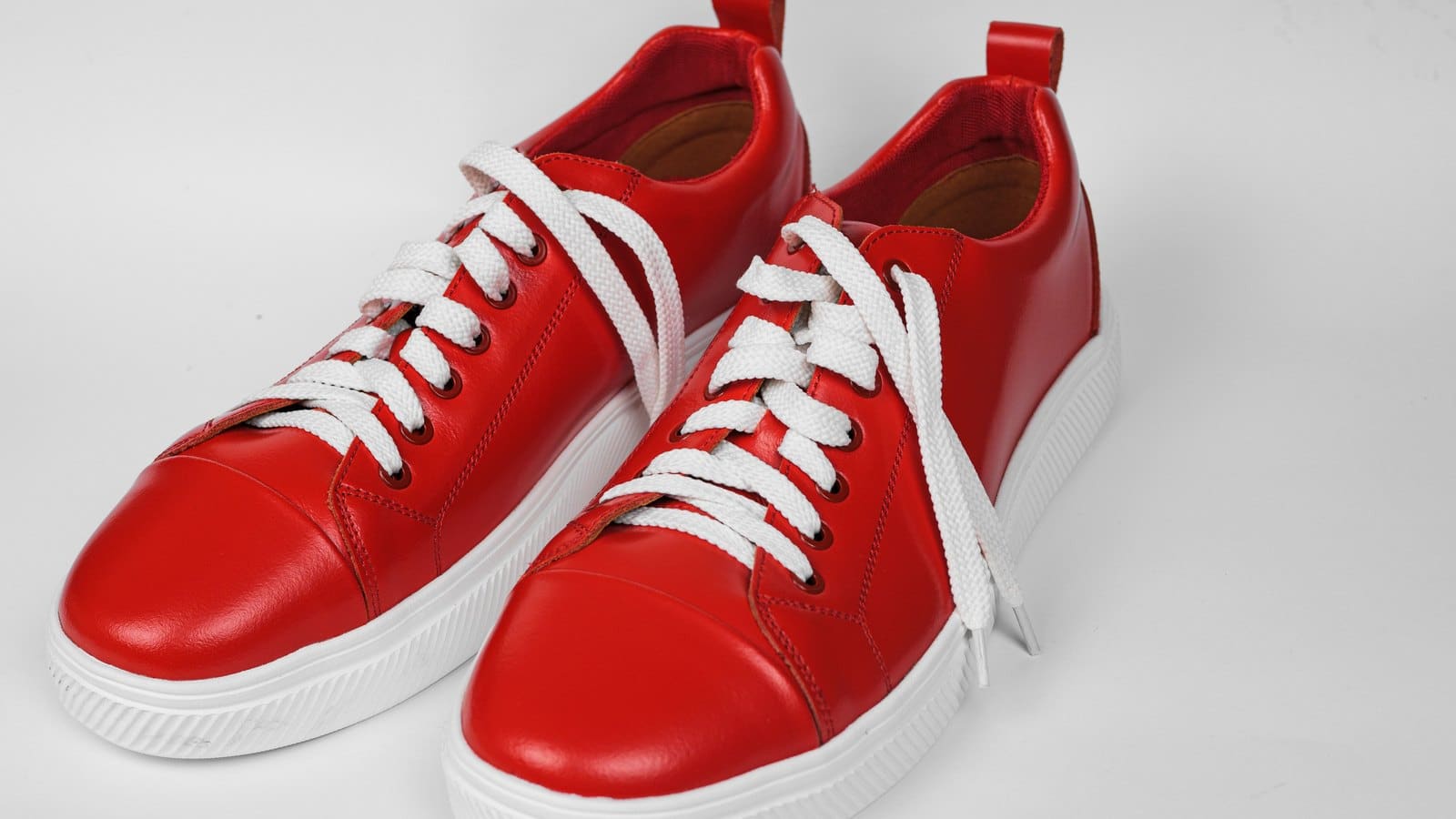 Paire de sneakers rouges en cuir à lacets blancs vue de profil