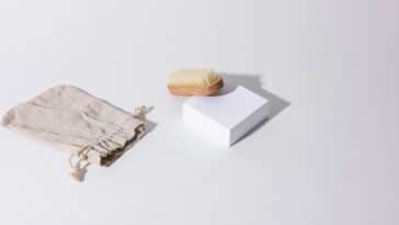 Brosse en bois, savon et pochette en toile posés sur fond clair