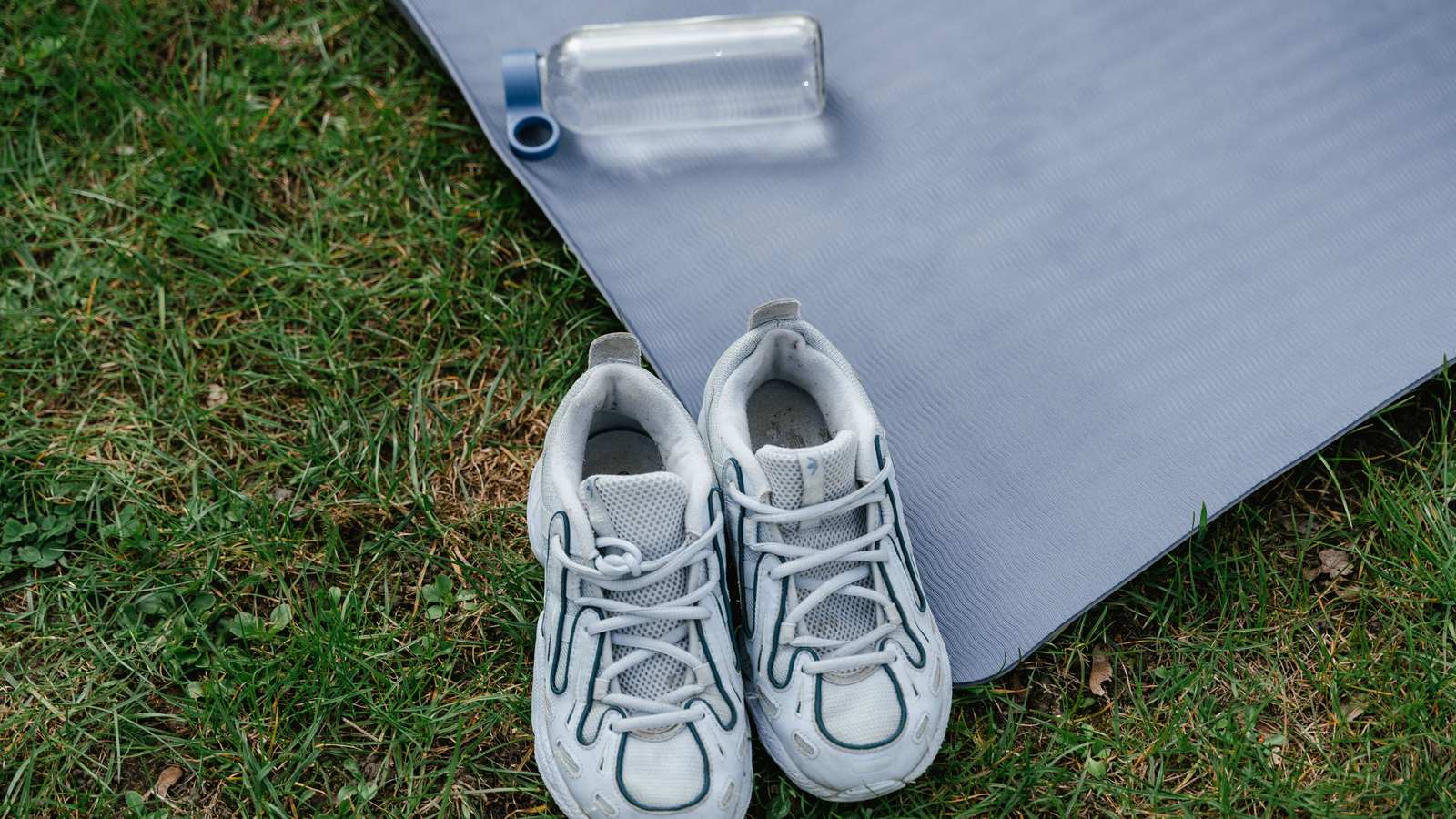 Paire de sneakers blanches posées à côté d'un tapis de sport