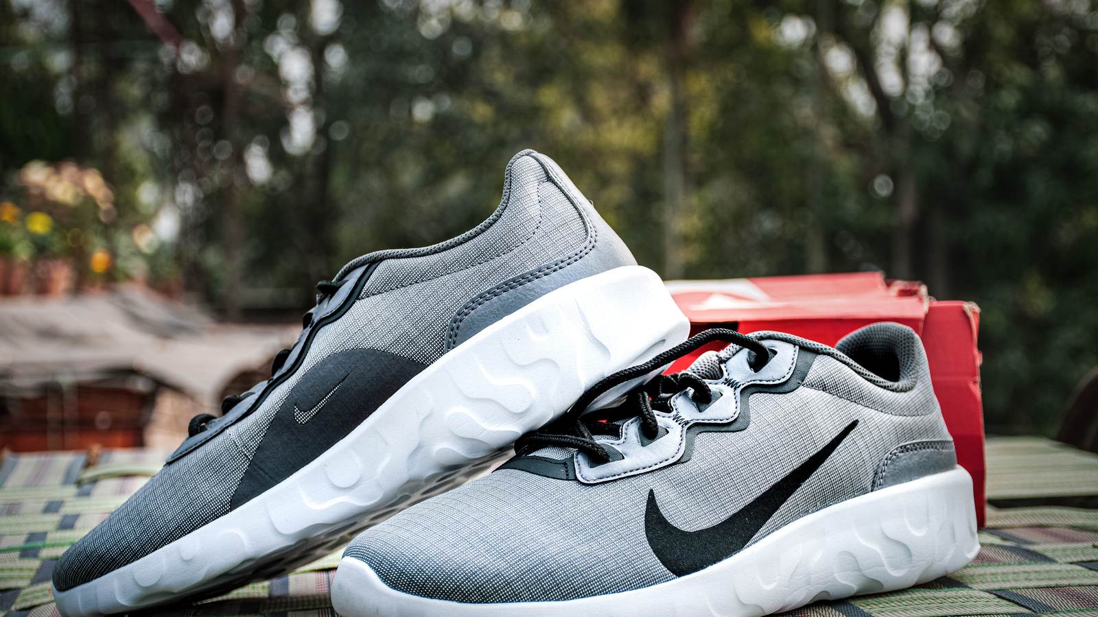 Paire de sneakers Nike grises et blanches devant une boîte rouge
