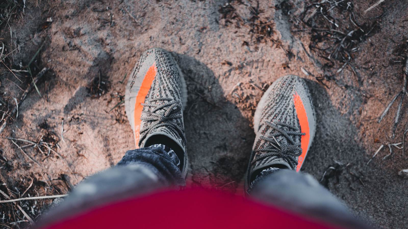 Pieds en sneakers vus du dessus sur un sol de terre