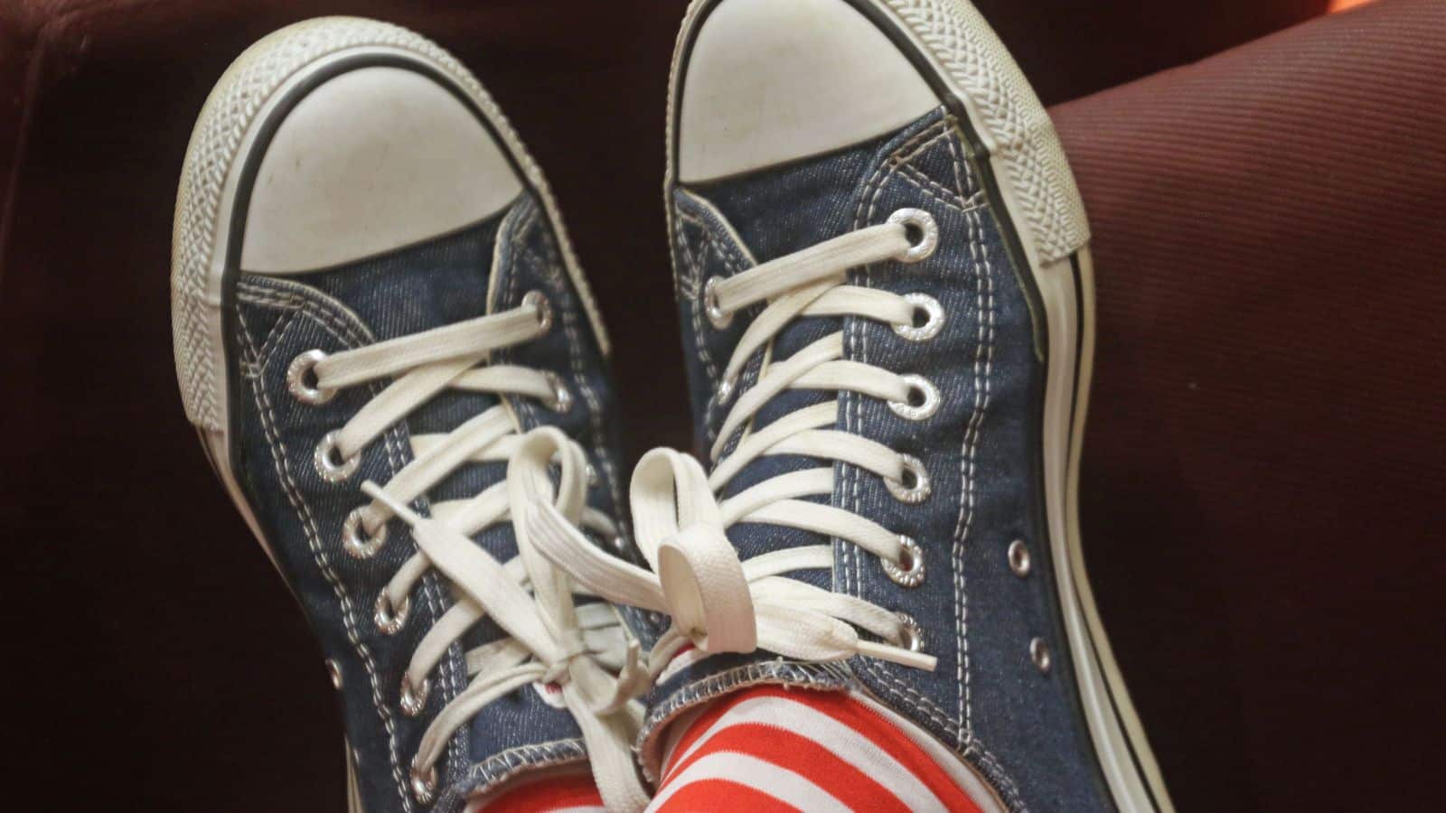 Sneakers montantes en toile bleue à lacets blancs, portées avec des chaussettes rayées