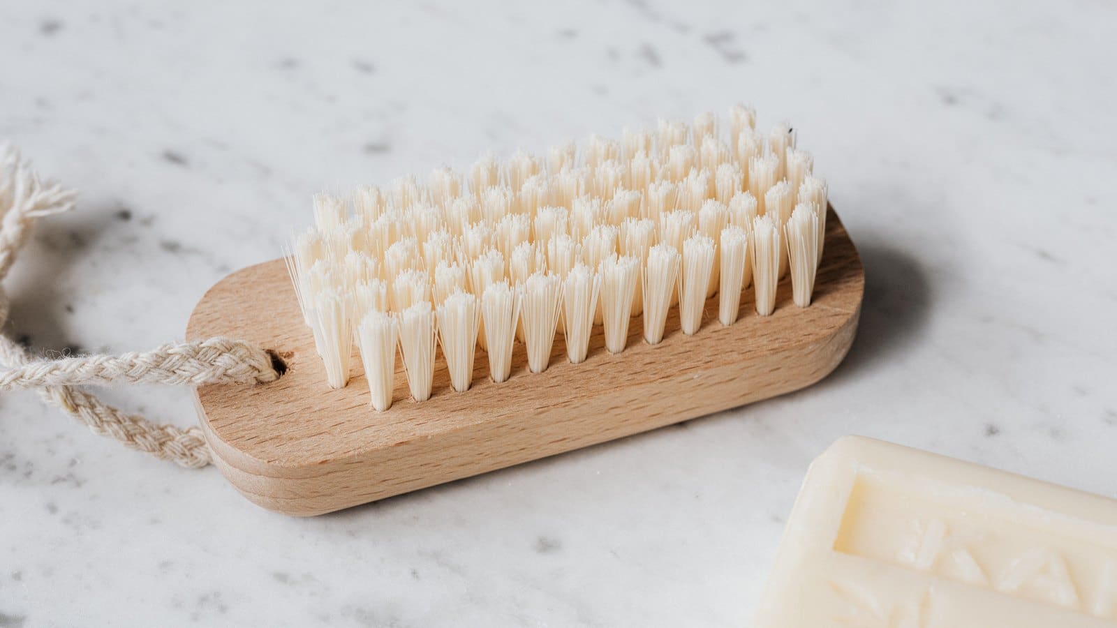 Brosse à poils clairs en bois et savon posés sur un plan en marbre