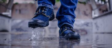 Sneakers bleues éclaboussant une flaque d'eau sur un sol mouillé