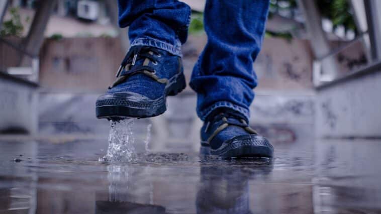 Sneakers bleues éclaboussant une flaque d'eau sur un sol mouillé